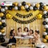 Birthday party setup with DECORATIONkart’s 66 pcs decoration kit featuring a black cardstock “Happy Birthday” banner, golden fringe curtains, metallic balloons in golden, black, and silver, golden star foils, and DIY accessories.