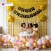 Birthday party setup with DECORATIONkart’s 66 pcs decoration kit featuring a black cardstock “Happy Birthday” banner, golden fringe curtains, metallic balloons in golden, pink, and white, golden star foils, and DIY accessories.