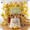 Birthday party setup with DECORATIONkart’s 66 pcs decoration kit featuring a blue cardstock “Happy Birthday” banner, golden fringe curtains, metallic balloons in golden, yellow, and white, golden star foils, and DIY accessories.