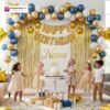 Indian children celebrating a birthday party with DECORATIONkart’s 66 pcs decoration combo set, featuring a golden foil “Happy Birthday” banner, golden fringe curtains, metallic balloons in gold, blue, and white, golden star foil balloons, and DIY accessories.