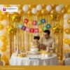 Birthday party setup with DECORATIONkart’s 66 pcs decoration kit featuring a multicolor cardstock “Happy Birthday” banner, golden fringe curtains, metallic balloons in golden, yellow, and white, golden star foils, and DIY accessories.