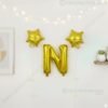 Golden foil balloon combo featuring letter 'N' (16 inch) and two star-shaped balloons (9 inch) for party decoration