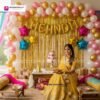 Mehndi ceremony setup with DECORATIONkart’s 59 pcs decoration kit featuring a golden foil “Mehndi” banner, golden fringe curtains, metallic balloons in golden, pink, and white, multicolor star foils, and DIY accessories.
