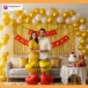 Anniversary party setup with DECORATIONkart’s 69 pcs decoration kit featuring a red cardstock “Happy Anniversary” banner, golden fringe curtains, metallic balloons in golden, yellow, and white, golden and red heart foils, and DIY accessories.