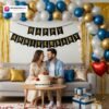 Anniversary party setup with DECORATIONkart’s 69 pcs decoration kit featuring a black cardstock “Happy Anniversary” banner, golden fringe curtains, metallic balloons in golden, blue, and white, golden and red heart foils, and DIY accessories.