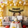 Anniversary party setup with DECORATIONkart’s 69 pcs decoration kit featuring a black cardstock “Happy Anniversary” banner, golden fringe curtains, metallic balloons in golden, yellow, and white, golden and red heart foils, and DIY accessories.
